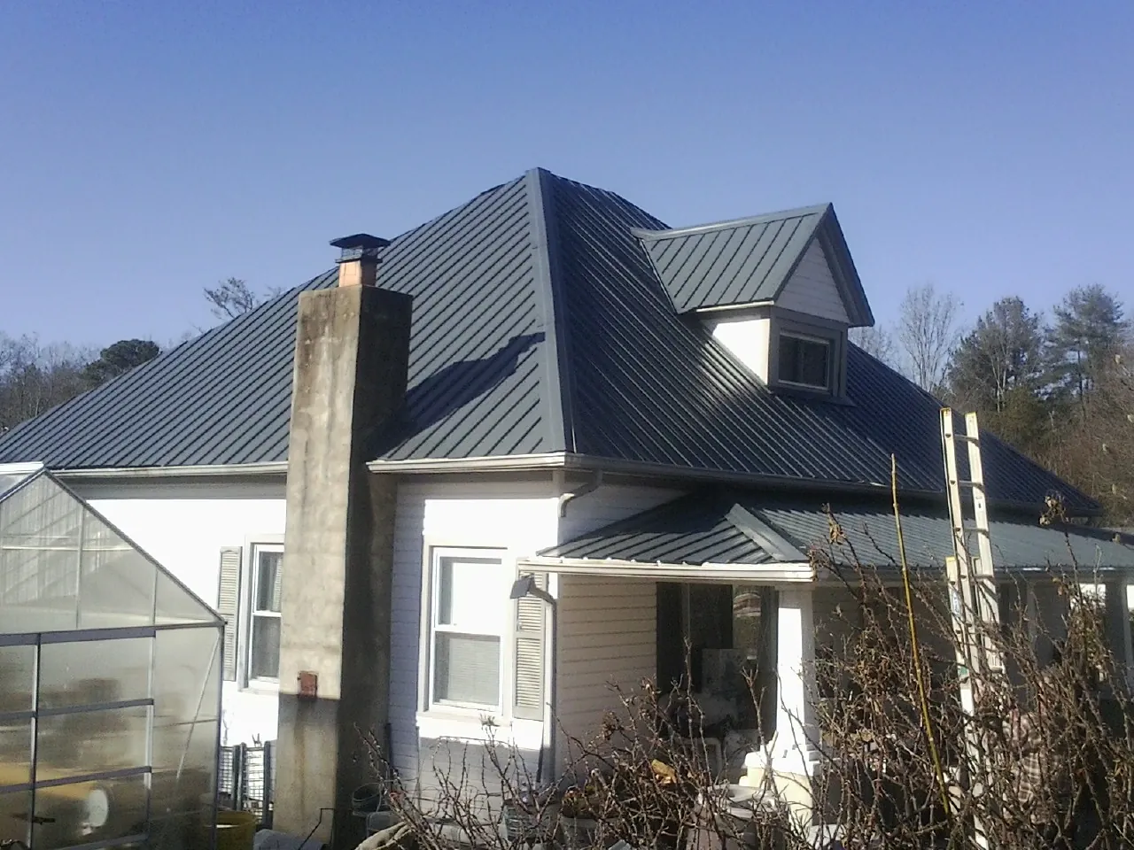 Dark blue standing seam metal roof on a white farmhouse with dormer — Slate & Tile Roof Repair by Roofing Brothers in Willet