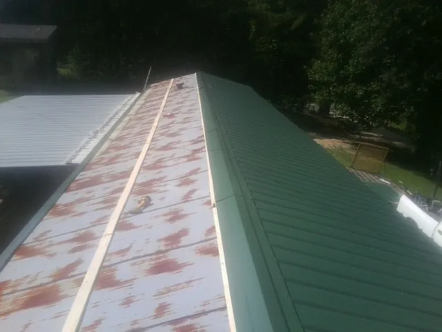 Old rusted panels beside newly installed green metal roofing — Wind Damage Roof Repair by Roofing Brothers in Willet