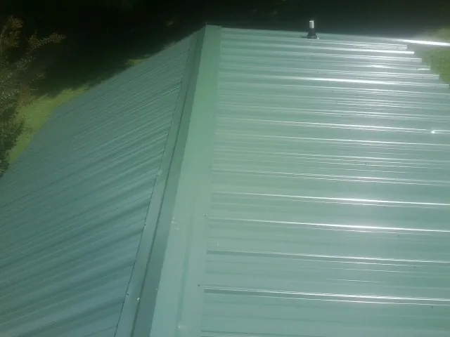 New green metal panels meeting at the ridge of a roof — Flat Roof Repair work by our crew in Willet