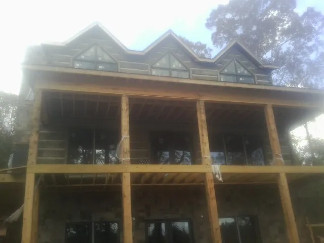 Dormers and porch framing on a large log home under construction — Roof Coating work by our crew in Willet