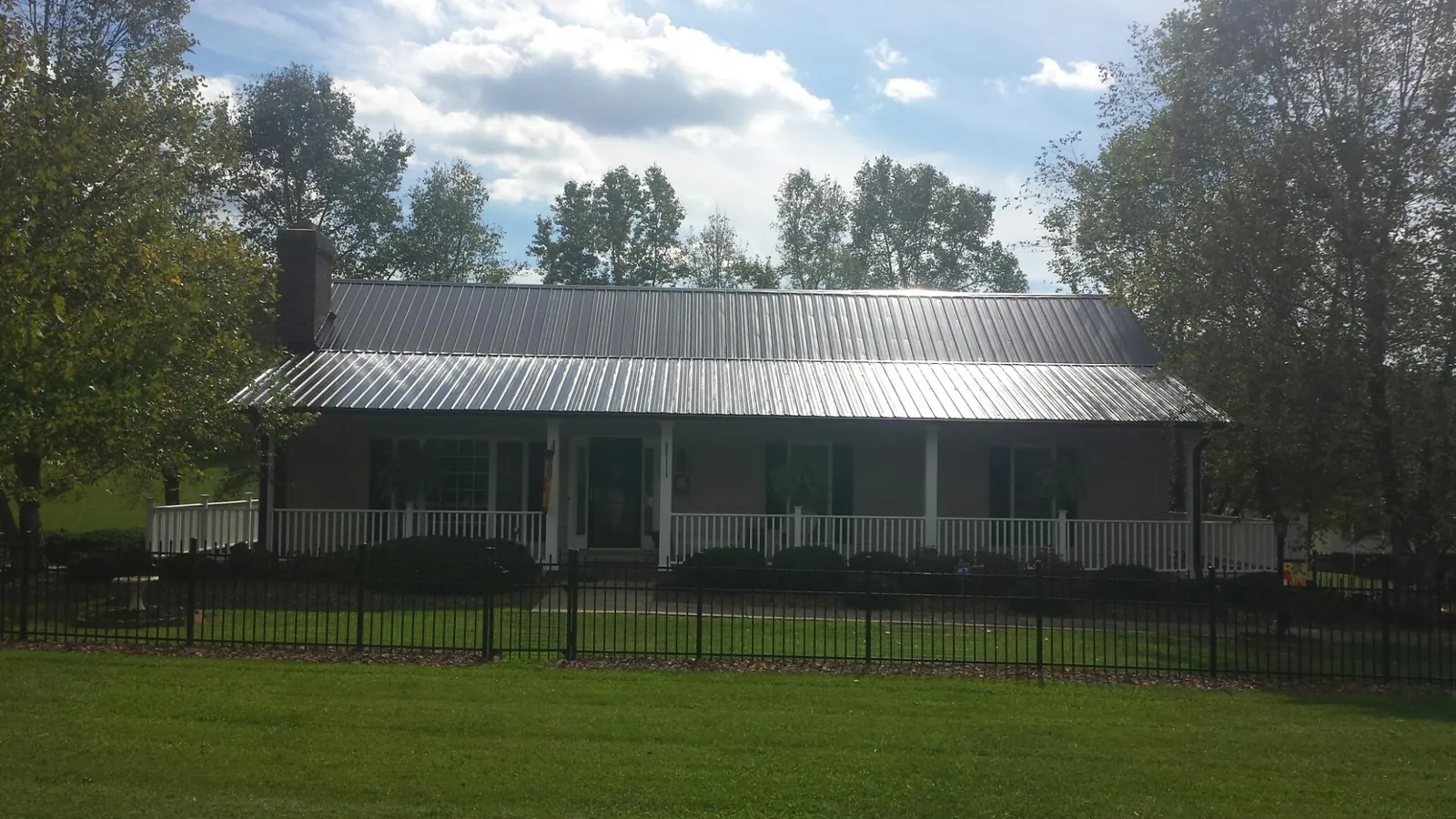 Gray metal roof on a brick ranch with a full width front porch — Gutter Guard Installation work by our crew in Willet