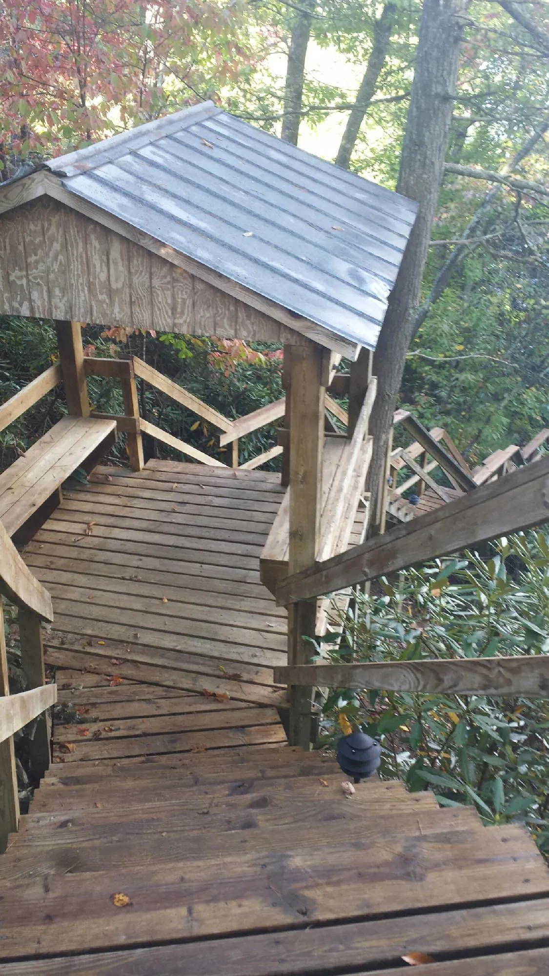 Metal roofed shelter over wooden steps on a wooded walkway — Skylight Repair & Installation work by our crew in Willet