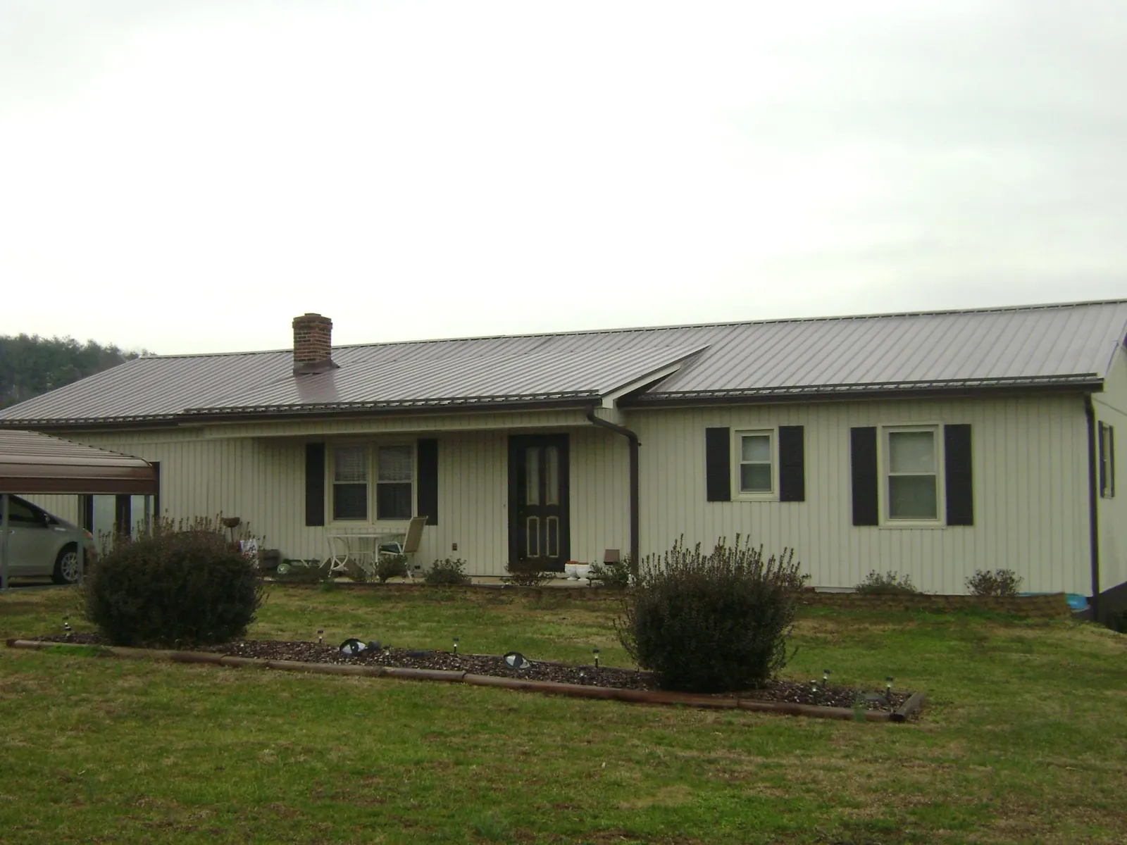 Brown metal roof on a cream sided ranch home with a brick chimney in Willet