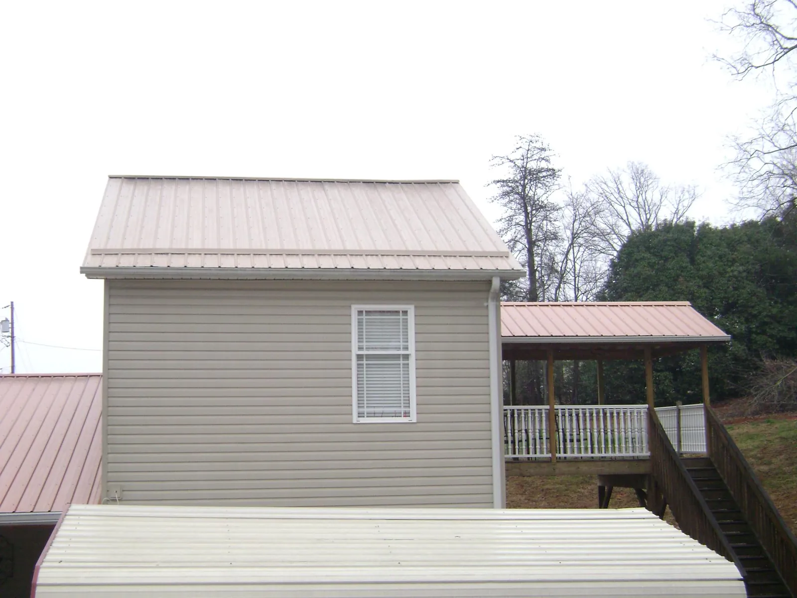 Tan metal roofs on a two story addition and attached porch, from a Roof Replacement job in Willet