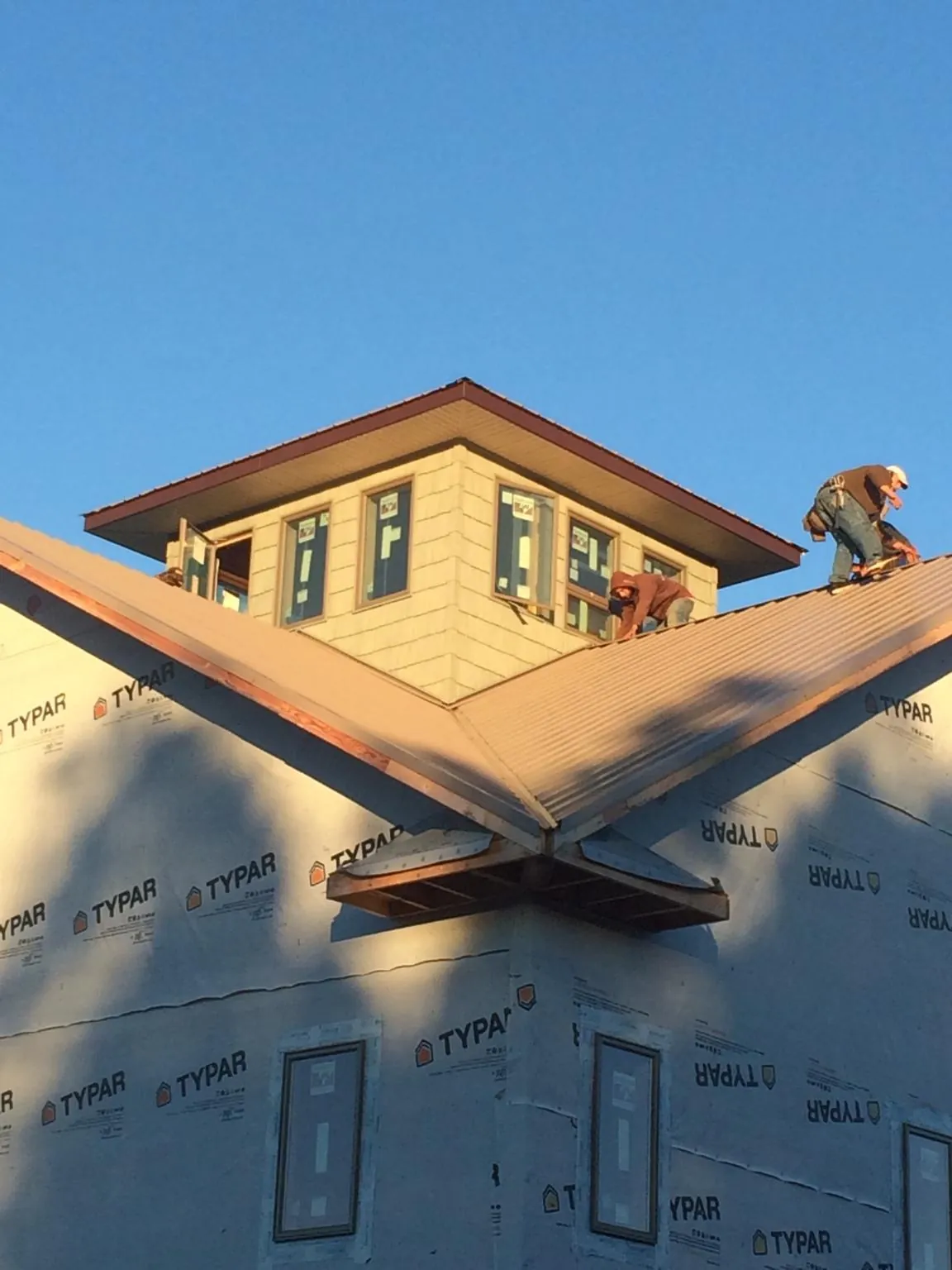 Roofers working around a rooftop cupola on a new metal roof at sunset — Roof Waterproofing in Willet by Roofing Brothers